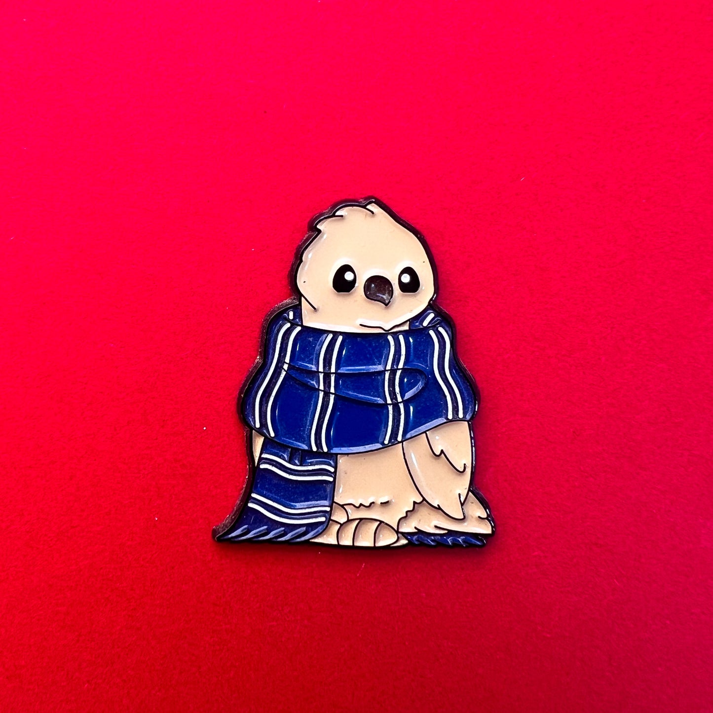 Pin de Ravenclaw: águila dulce con bufanda azul y bronce. ¡Perfecto para amantes de la sabiduría!