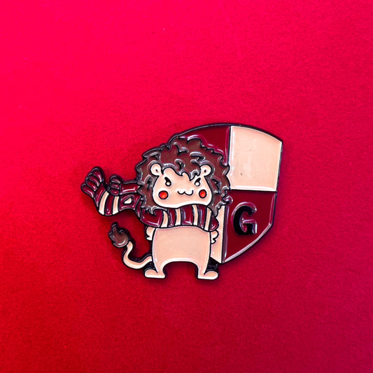 Pin de Gryffindor con un león tierno sobre el escudo de la casa, en tonos rojos y dorados.
