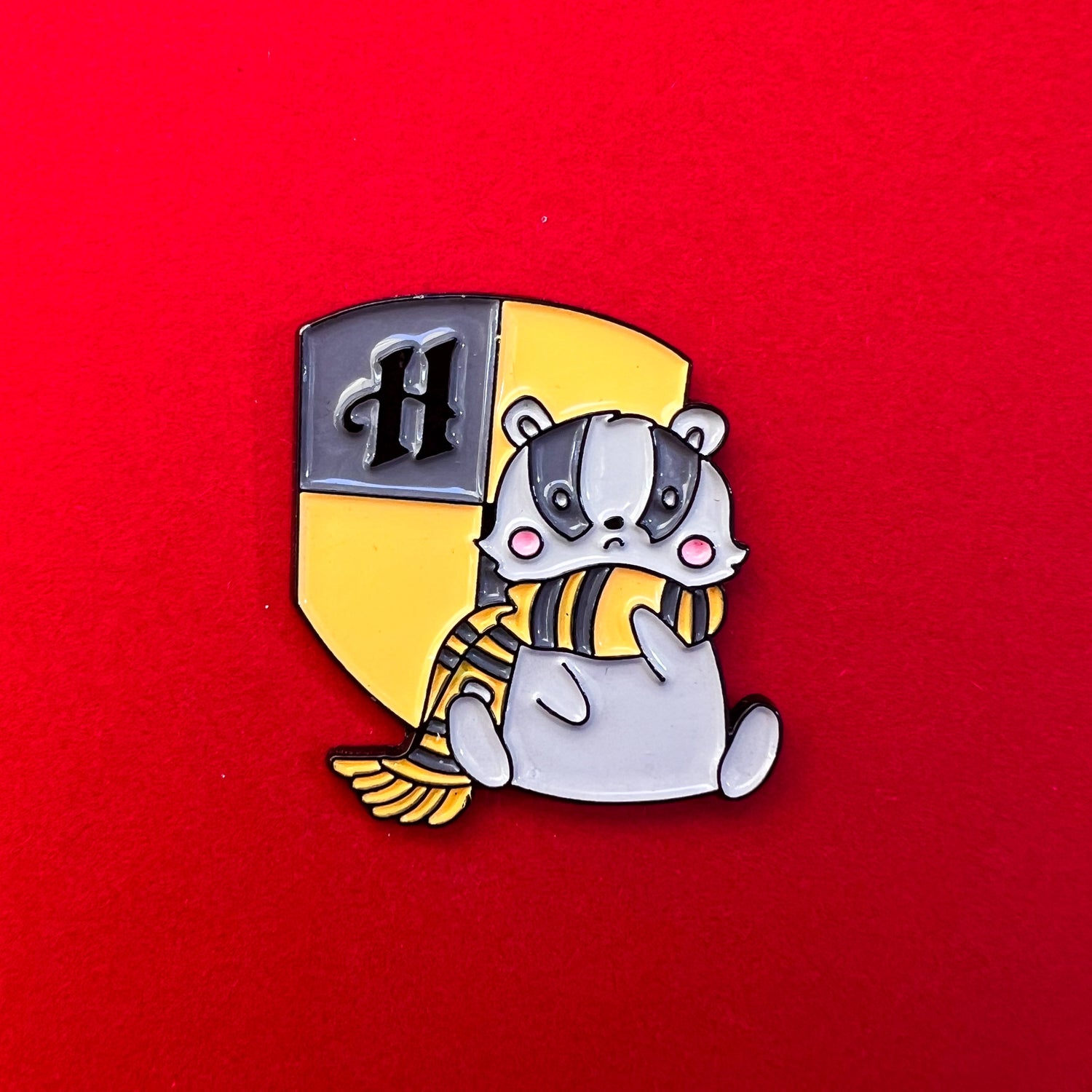 Pin de Hufflepuff con un tejón dulce sobre el escudo de la casa, en tonos amarillos y negros.